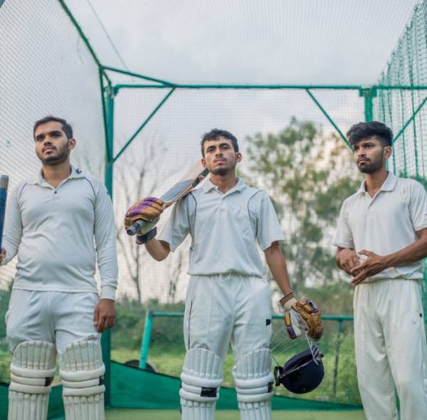 Cricket players standing a giving team poses in cricket nets in practice time